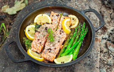 Healthy baked salmon steaks with greens and asparagus in a black cast iron skillet. A delicious low-carb breakfast.