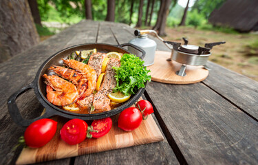 Baked salmon steaks with herbs and asparagus in a black cast iron skillet.
