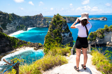 A photographer capturing the scenic view of a blue ocean from a cliffside, surrounded by lush greenery.