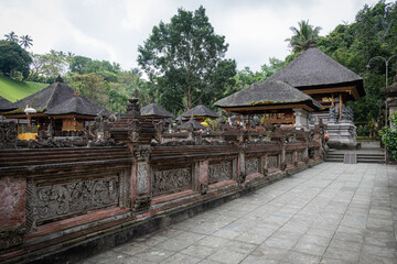 Pathway through the grounds of a Balinese temple, surrounded by traditional structures and lush vegetation.