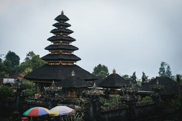 A traditional Balinese temple with a multi-tiered roof on a cloudy day.