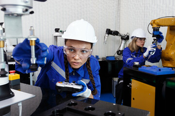 female automation machine engineer student study and operating control robot arm machine in...