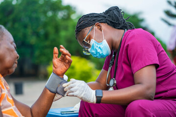 image of health worker checking up blood pressure outside - personal support worker assisting...