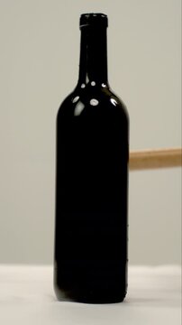 bottle of red wine smashed with a stick in vertical