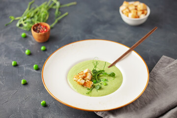 Green peas cream soup in plate. Summer vegetable food