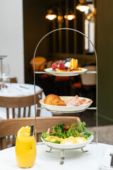  Elegant tea set with tiered stand with French wholesome breakfasts of fresh fruit, pastries, fresh vegetables and poached eggs in an upscale restaurant setting. High quality photo