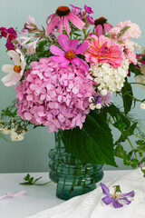 A bouquet of summer flowers in the room. Hydrangea, rose, echinacea, mint, snapdragon, asparagus and other flowers.