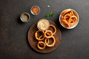 Heap of deep fried onion rings on wooden serving dish