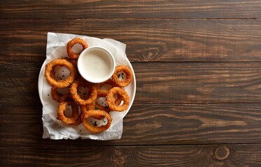 Heap of deep fried onion rings with sauce