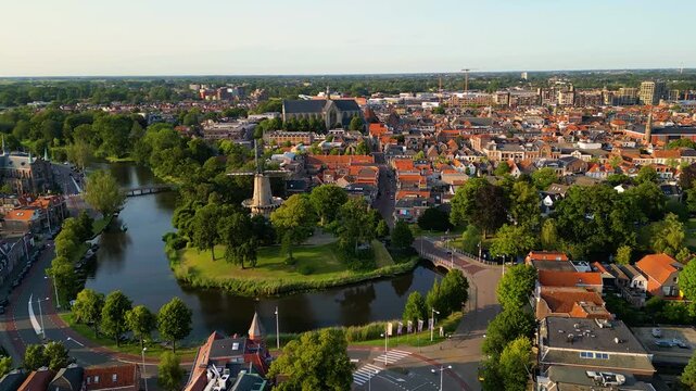 High angle Drone Point of View on Old Windmill in Downtown Area of Alkmaar, North Holland, The Netherlands on summer evening in July, flying forward.
