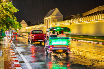 A nighttime view of a long exposure busy city street with cars, taxis, tuktuk and blurred lights, Bangkok, Thailand.