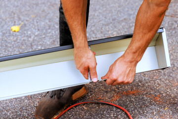 Worker installing hidden gutter hangers with a pre inserted screw heavy duty rain gutter brackets...
