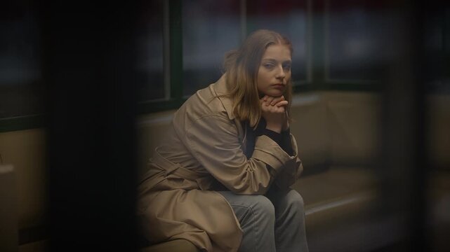 A woman in a coat sits alone on a bench, lost in contemplation, creating a tranquil city scene