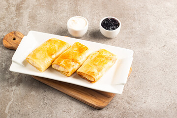 Thin pancakes stuffed with cottage cheese served with sour cream and black currant jam. French crepes. 