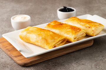 Thin pancakes stuffed with cottage cheese served with sour cream and black currant jam. French crepes. 