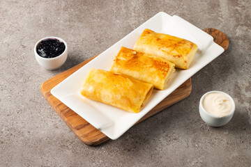 Thin pancakes stuffed with cottage cheese served with sour cream and black currant jam. French crepes. 