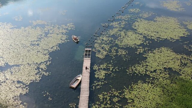 Old wooden pier with boat on Plavsko lake between water lilies, Montenegro, Europe