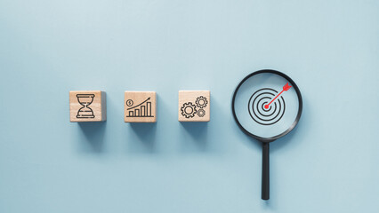 A wooden cube with hourglass, business graph and gear icon with red arrow hit target pointing at...