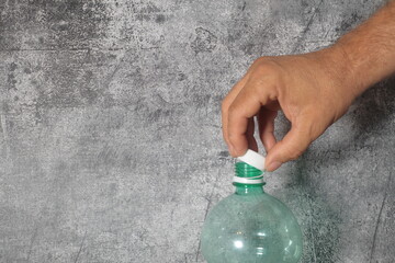 mano abriendo tapon adosado botella verde plastico