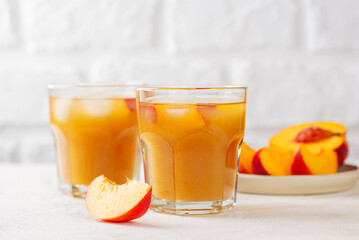 Fresh peach and nectarine iced tea. Iced tea with peach slices and ice cubes on white background. Juice, cocktail, lemonade made from peach.