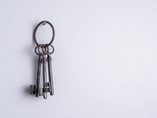 Vintage, rusty, iron keys with a ring on a white wall.
