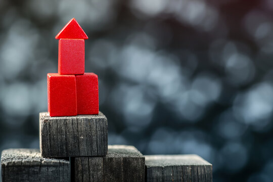 A tower of red and black blocks standing on a dark surface with a blurry background, symbolizing balance.