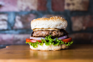Grilled Beef Burger include grill beef patty, mayonnaise, lettuce leaf, tomato and onion isolated on wooden board side view of unhealthy junk fastfood