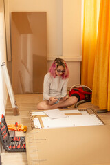 teenager recognizing furniture assembly parts, seated on the floor