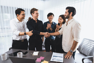 Diverse group of office employee worker shake hand after making agreement on strategic business marketing meeting. Teamwork and positive attitude create productive and supportive workplace. Prudent