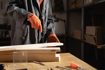 Skilled Carpenter Drilling Wooden Planks in Workshop