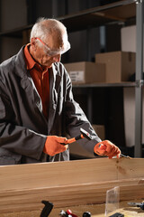 Senior Carpenter Shaping Wood with Chisel and hammer