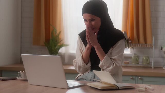 Sad upset frustrated crying Arabian woman Indian business girl Muslim female Islamic lady homeowner householder in hijab laptop problem work trouble debt loan unemployment suffer lost pray at kitchen