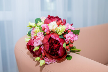 Wedding flowers, red color, bridal bouquet closeup. Decoration made of roses, hypericum and decorative plants, red peonies close-up, selective focus.Florist shop in daylight.