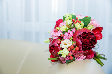 Wedding flowers, red color, bridal bouquet closeup. Decoration made of roses, hypericum and decorative plants, red peonies close-up, selective focus.Florist shop in daylight.