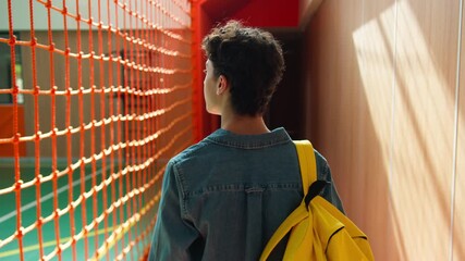 Back view from behind unrecognizable Caucasian student guy boy school pupil male man teen schoolboy teenager with schoolbag backpack walking in sport hall university college walk go education studying - Powered by Adobe