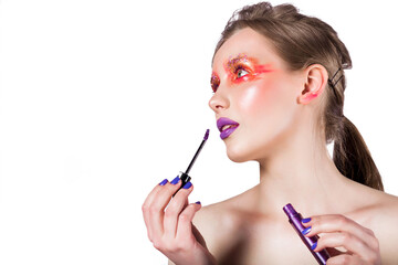 Woman Applying Purple Lip Gloss. A woman with vibrant eye makeup and glossy purple lipstick applies...