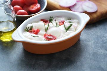 Flat bread Italian cuisine focaccia ready to bake with tomatoes, rosemary, purple onion on a concrete background. top view. Healthy sourdough bread