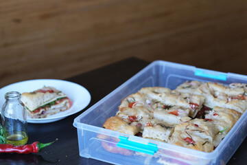 Handmade Italian bread with vegetables, cut into portions in a plastic container ready for storage. Healthy sourdough bread.