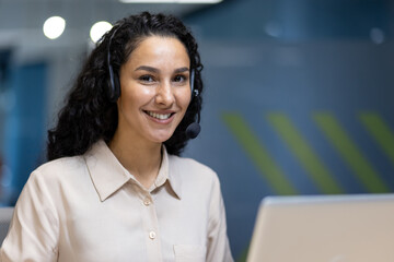Smiling woman wearing headset offering customer service from modern office. Professional support...