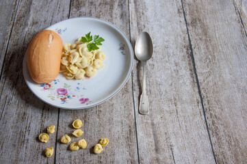 Pasta and bread on a white plate on a wooden background.