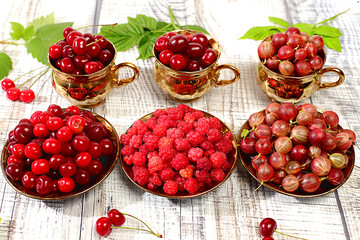 Summer fresh berries, cherries, gooseberries and raspberries on a wooden background with leaves, banner for shops, rustic harvest, healthy natural food concept, breakfast with ingredients,.