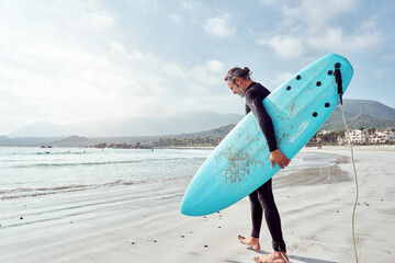 surfist mature man with surfboard walking on the shore, entering the water, healthy lifestyle and anti aging concept.