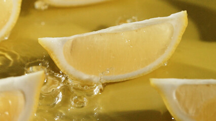 Top down view of lemon slices splashing in water on yellow background. Close up of fresh lemon sliced placing at separated yellow background with water pouring and splash. Citrus freshness. Pabulum.