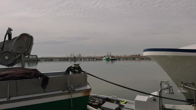 Fishing boats and ships in the port of Castellon in winter. Port cranes on the horizon. Floats for nets. Port of El Grao. Spain. High quality 4k footage