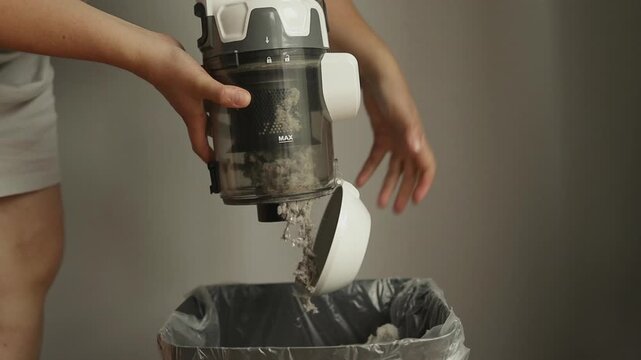 Female opening dust filter out of vacuum cleaner at home. Hoover container full of dirt, fur, pet hair after cleaning at home. Dust in apartment is source of allergies. Household chores concept. High