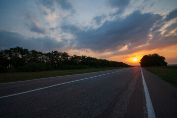 Asphalt road on sunset in the field.