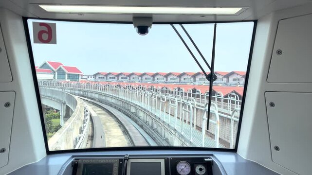 View from inside a modern train cockpit as it approaches a station. The control panel and front window highlight advanced technology and contemporary design.