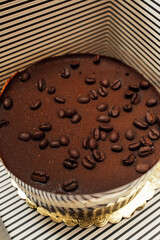 gourmet store bought tiramisu cake with coffee bean garnish, in black and white striped box