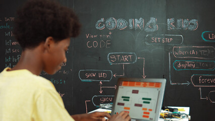 African boy using laptop programing system or coding prompt at blackboard with science theory....