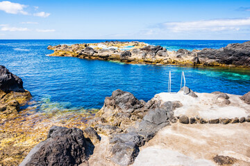 Obraz premium Natural pools with rocks and turquoise ocean water at Capelinhos peninsula on coast of Faial island, Azores, Portugal, Faial island, Azores, Portugal